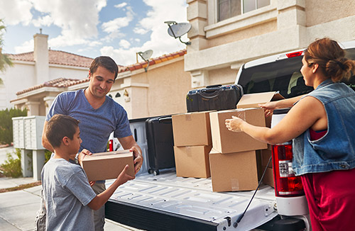 Family moving boxes from truck bed